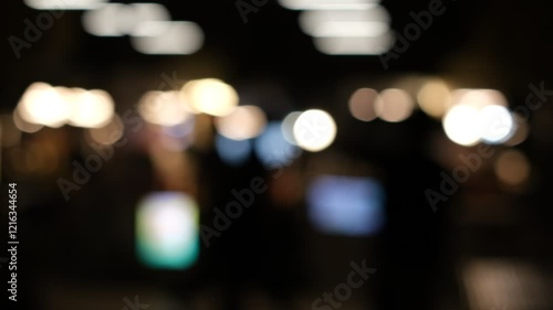A blurry image of a crowd of people in a dark room. Scene is mysterious and somewhat ominous