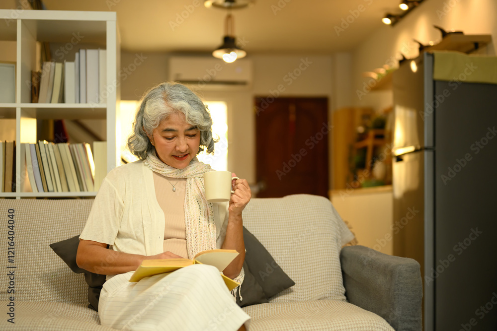 Peaceful elderly woman reading book and sipping from a mug Peaceful elderly woman reading book and sipping from a mug