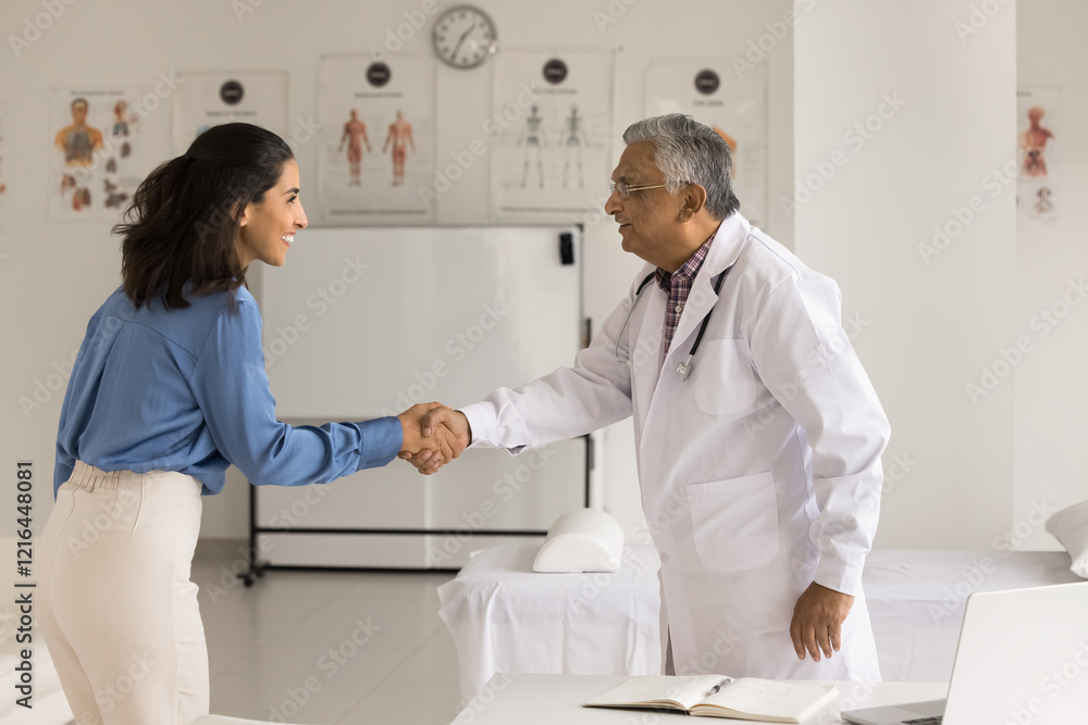 Fototapeta premium Partnership in healthcare. Happy mature man doctor medic worker young woman patient pharmaceutical company representative shake hands on meeting at clinic glad satisfied with successful collaboration