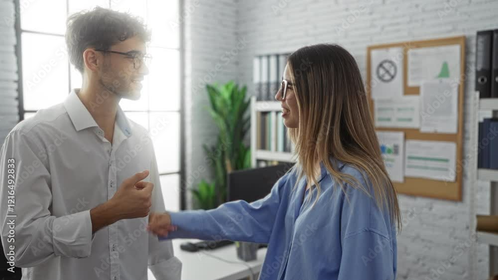 Business man and woman fist bumping in a modern office, showcasing teamwork and success in a professional workplace environment, with shelves and plants in the background. Business man and woman fist bumping in a modern office, showcasing teamwork and success in a professional workplace environment, with shelves and plants in the background.