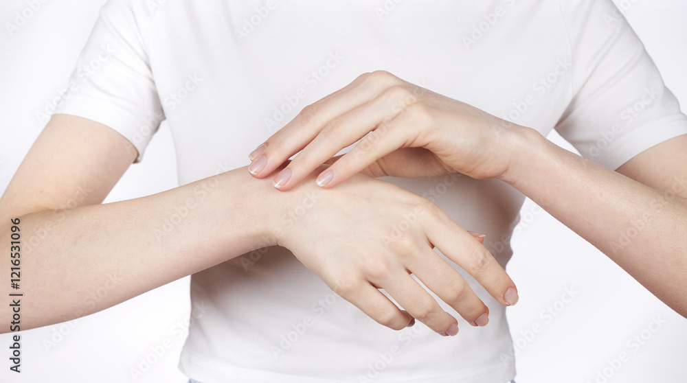 A young girl rubs cosmetic cream for care and moisturizing onto the skin of her hands. A young girl rubs cosmetic cream for care and moisturizing onto the skin of her hands.