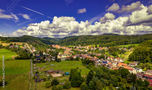 Obraz na płótnie Vibrant German Village Nestled in a Valley Surrounded by Lush Greenery and Picturesque Mountains on a Bright Sunny Day w salonie