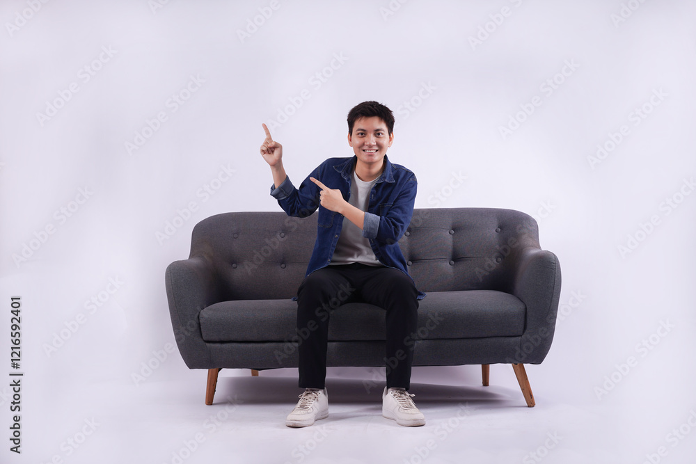 Full body image of young Asian man posing on sofa on white background Full body image of young Asian man posing on sofa on white background