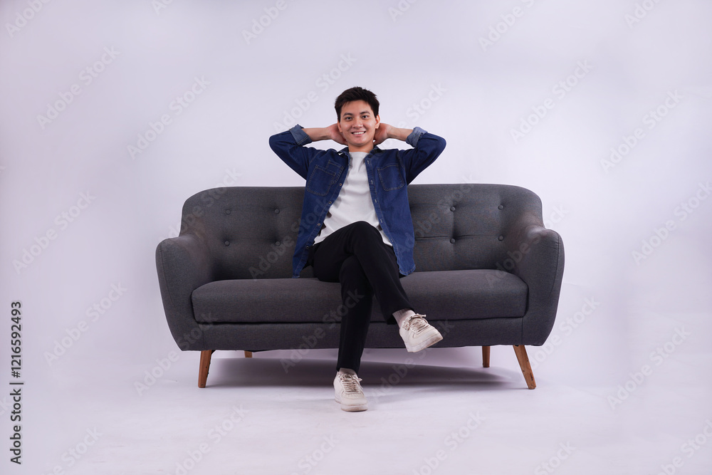 Full body image of young Asian man posing on sofa on white background Full body image of young Asian man posing on sofa on white background