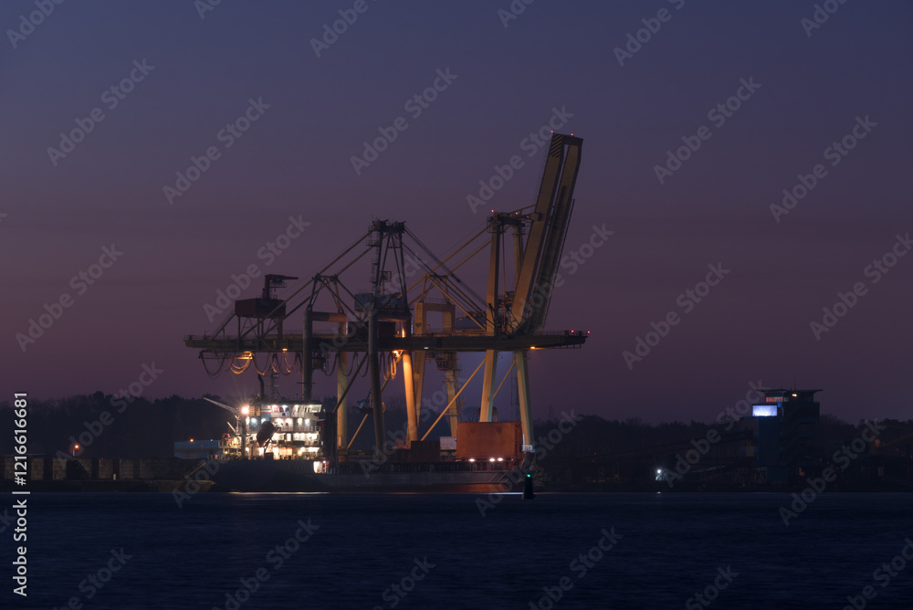 SEA PORT IN SWINOUJSCIE - The lighthouse and the quay of transshipment terminal at sunrise SEA PORT IN SWINOUJSCIE - The lighthouse and the quay of transshipment terminal at sunrise