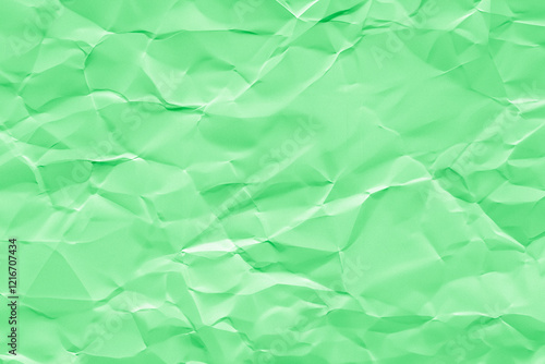 Creased or crumpled green colored paper background. Wrinkled blank sheet texture	
