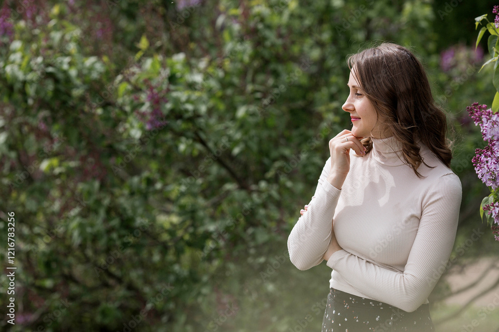 Spring blooming. Portrait of a pretty 30-year-old young woman in a blooming lilac garden in nature. Spring blooming. Portrait of a pretty 30-year-old young woman in a blooming lilac garden in nature.