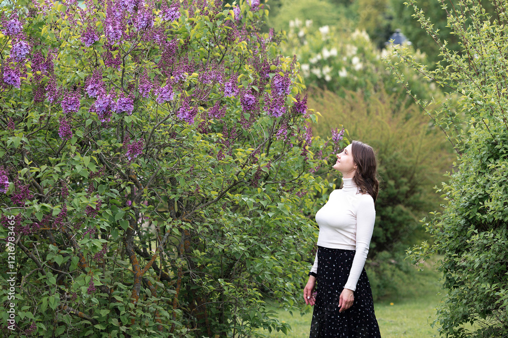 Spring blooming. Portrait of a pretty 30-year-old young woman in a blooming lilac garden in nature. Spring blooming. Portrait of a pretty 30-year-old young woman in a blooming lilac garden in nature.