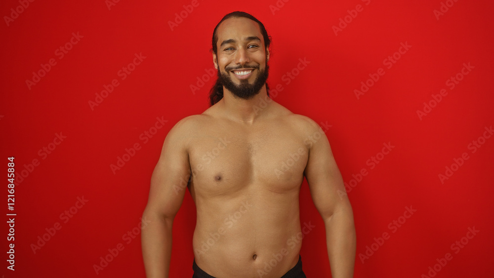 Fototapeta premium Young man with beard smiling confidently against an isolated red background showcasing strength and vitality