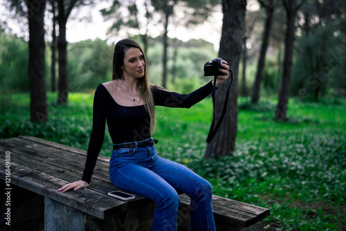 Obraz na płótnie Chica joven delgada vloggeando con cámara por zona verde con arboles w salonie