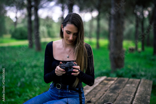 Obraz na płótnie Chica joven delgada vloggeando con cámara por zona verde con arboles w salonie