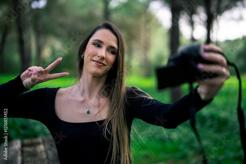 Obraz na płótnie Chica joven delgada vloggeando con cámara por zona verde con arboles w salonie