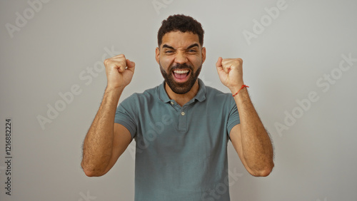 Young hispanic man celebrating over white background with excited expression and fists raised in the air conveying success and joy photo