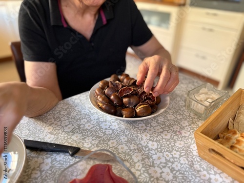 Old woman hands peeling roasted chestnuts