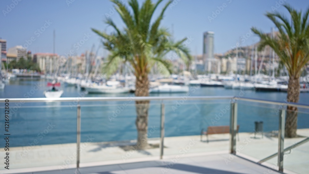 Fototapeta premium Blurred outdoor scene with defocused palm trees, boats, and a marina view with a blue sky in the background.