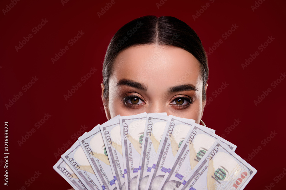 Photo of pretty mysterious woman hold dollar bills cover face isolated on maroon color background Photo of pretty mysterious woman hold dollar bills cover face isolated on maroon color background