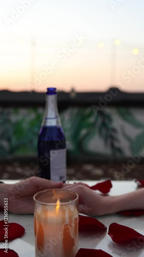 Romantic dinner setting with champagne glass, candlelight, rose petals at sunset, elegant outdoor dining experience concept