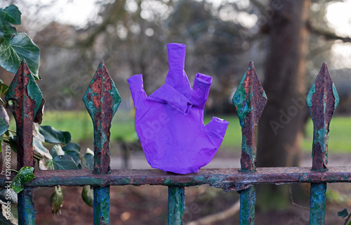 A discarded disposable rubber glove on rusted park railings