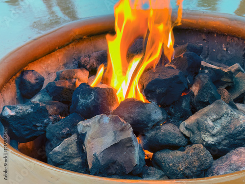 Natural gas fire pit with ceramic rocks and flames photo