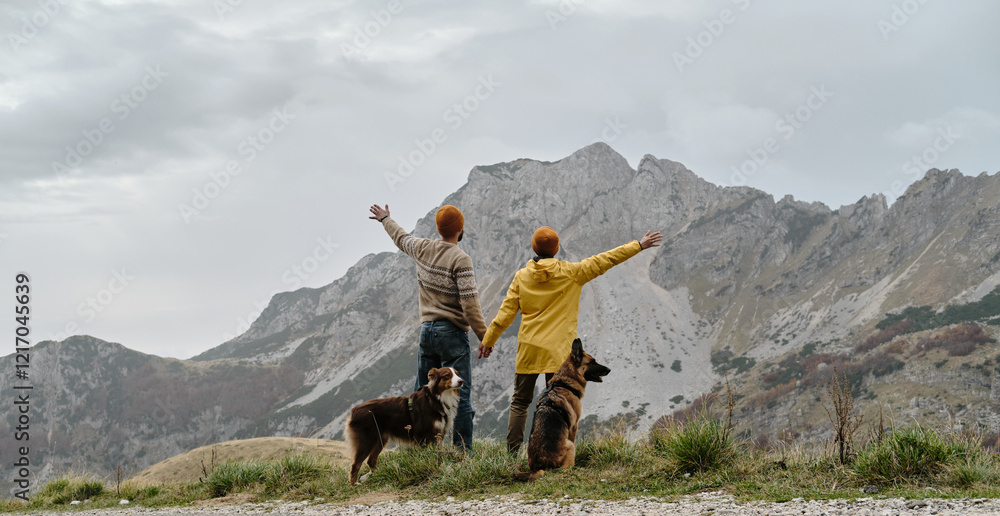 Obraz premium Breathtaking mountain landscape with traveling young couple and their dogs. Travel with pet concept. Montenegro country, Durmitor National Park. Saddle Pass. Alpine meadows in autumn season.