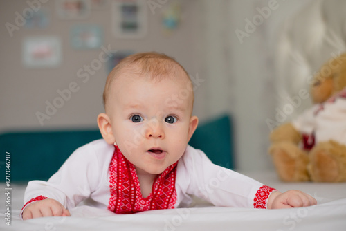 newborn baby boy lying on bed in Ukrainian embroidery at home surprised thoughtful