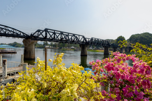 Selective focus of yellow pink Bougainvillea flowers on balcony with blurred the bridge of river Kwai, The historic bridge and railway line was built during the World War II, Kanchanaburi, Thailand. photo