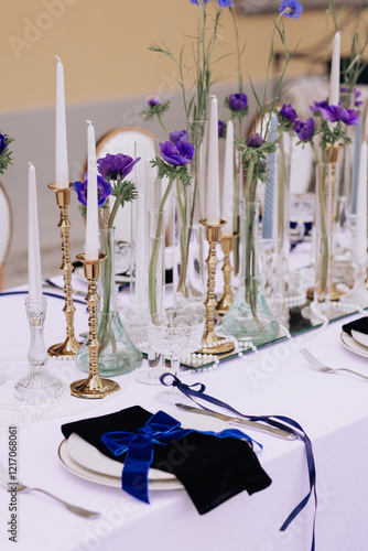 Elegant wedding table setting with purple floral arrangements, gold candleholders, and white tablecloth overlooking the lake