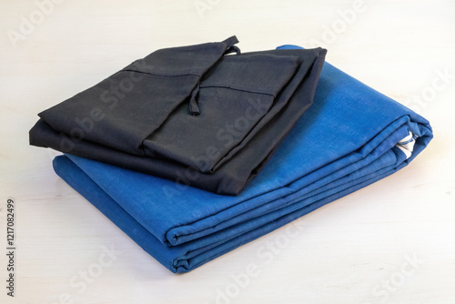 A folded blue cotton saree and black petticoat rest gracefully against a light wooden backdrop. photo