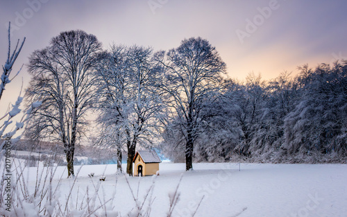 Kapelle im Schnee im Winter zwischen Bäumen