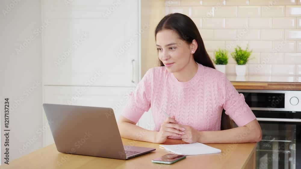 Beautiful young woman working with laptop computer in home kitchen. Work at home. Freelance, remote work Beautiful young woman working with laptop computer in home kitchen. Work at home. Freelance, remote work