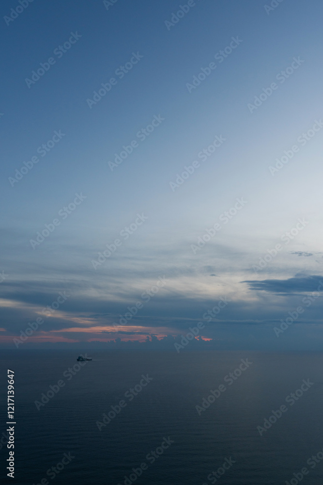 Seascape featuring a lone ship on the horizon under a twilight sky Seascape featuring a lone ship on the horizon under a twilight sky