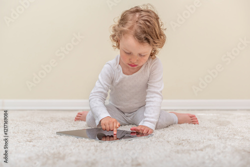 Little girl using a tablet in a cozy home environment. A small child playing with a tablet in a comfortable home setting.