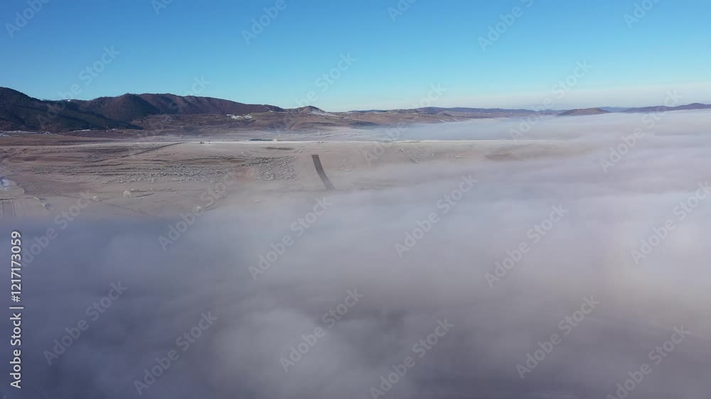 Aerial view of misty countryside hills at wintertime, morning fog above by drone Aerial view of misty countryside hills at wintertime, morning fog above by drone