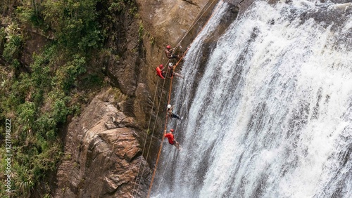 Принти на полотні Aerial shot of a group of people abseiling a high waterfall