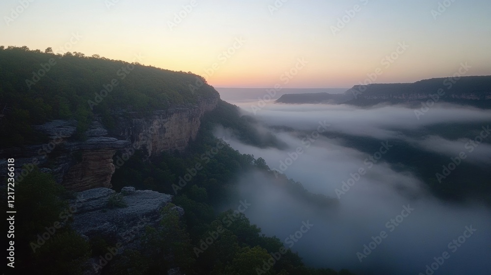Fototapeta premium A breathtaking sunrise over a deep canyon, with a thick layer of fog enveloping the valley below.