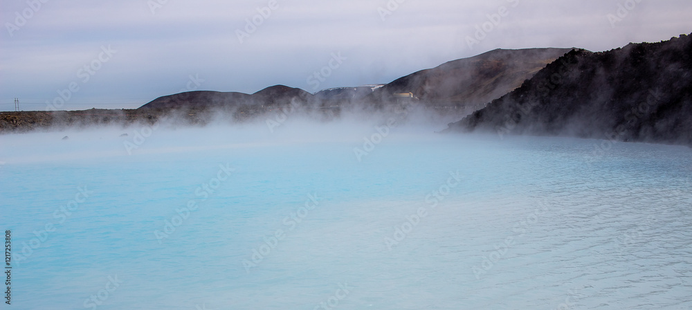 Blue water and lava rock mountains at the Blue Lagoon in Grindavik Iceland during a cloudy day Blue water and lava rock mountains at the Blue Lagoon in Grindavik Iceland during a cloudy day