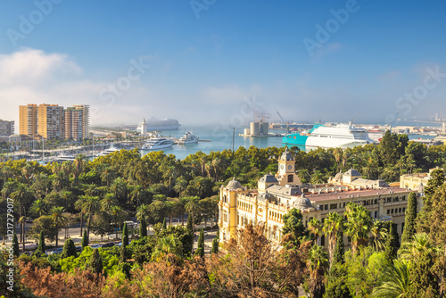 Malaga, seaside city in Andalusia, Spain, Europe. Coastal city harbor view with buildings and cruise ships. Lush greenery surrounds a grand building overlooking the water. photo