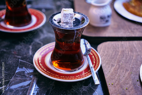 A traditional Turkish armud cup with tea on a saucer and the oriental sweet Turkish delight. Turkish-style breakfast with a cup of tea photo