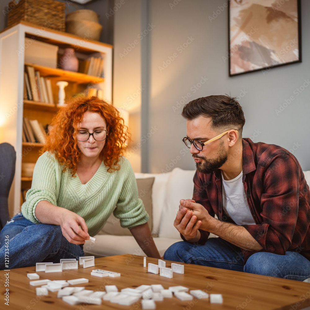 Fototapeta premium young adult couple enjoying domino together in the living room