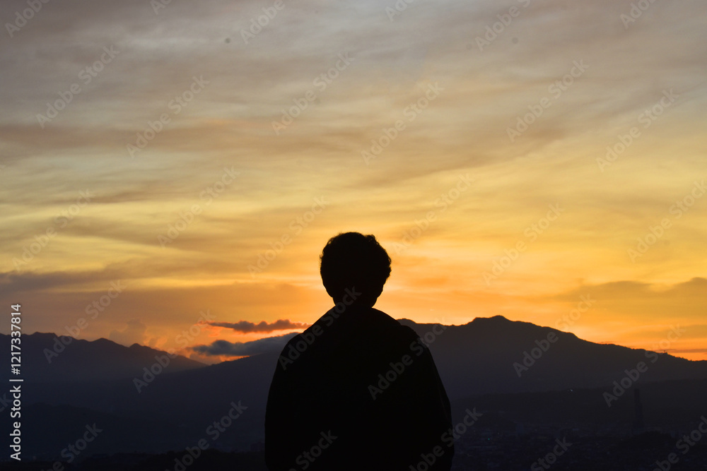 A Silhouette of a Person Gazing at a Vibrant Sunset Over the Mountains A Silhouette of a Person Gazing at a Vibrant Sunset Over the Mountains