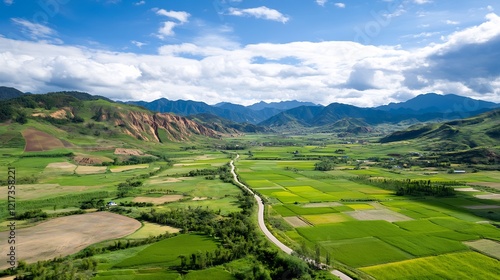 Aerial view of lush green fields and winding river in mountainous landscape