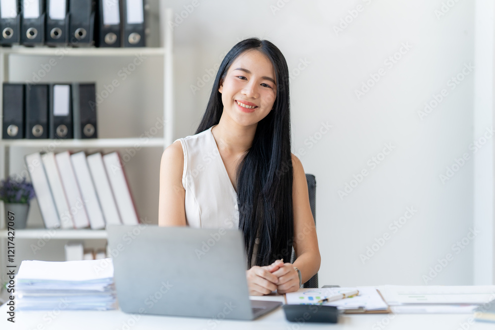 Confident Businesswoman at Desk: A portrait of a smiling Asian businesswoman sitting at her desk, confidently looking at the camera. She exudes professionalism and success. Confident Businesswoman at Desk: A portrait of a smiling Asian businesswoman sitting at her desk, confidently looking at the camera. She exudes professionalism and success.