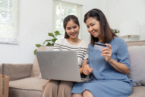 Two women shopping online together with a credit card, enjoying their experience at home