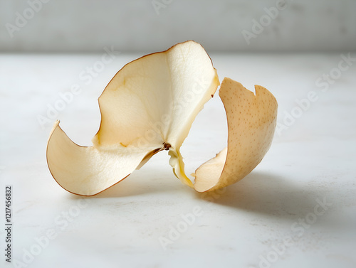 Close up of pear skin peel discarded on a kitchen counter with a textured white backdrop, the image captures the beauty of everyday objects and the delicate nature of fruit. photo