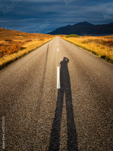 Shadow of a fotographer taking a foto of a road in a sunny landscape in Scotland
