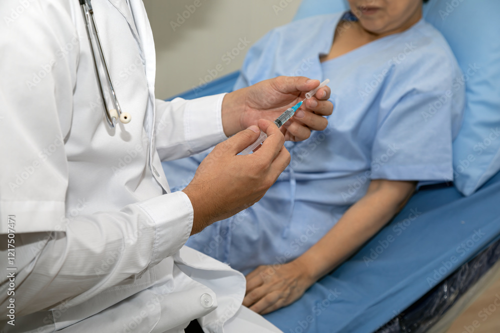 Doctor holding syringe and preparing for injection while senior patient in hospital gown lying on medical examination bed Doctor holding syringe and preparing for injection while senior patient in hospital gown lying on medical examination bed
