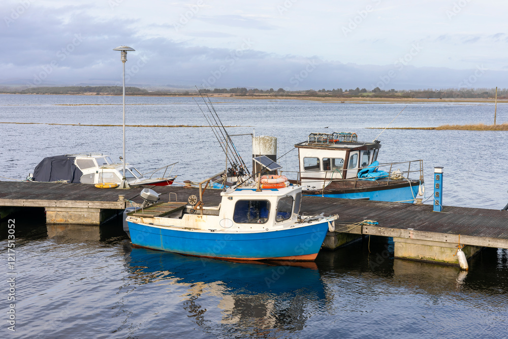 Fototapeta premium Small Fishing Boats Moored at a Dock in a Calm Harbor With Out Board Motors and Fishing Rods
