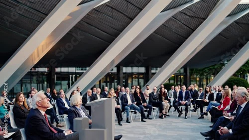 Business leaders gather for an outdoor conference in a modern architectural setting