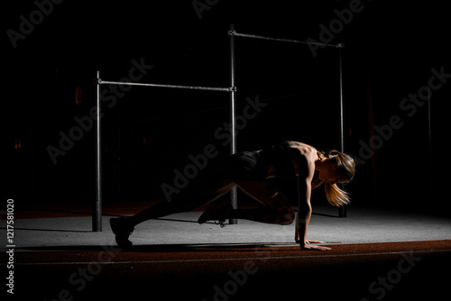 Female athlete stands in a horizontal position on her toes and toes with one leg bent in front of her photo