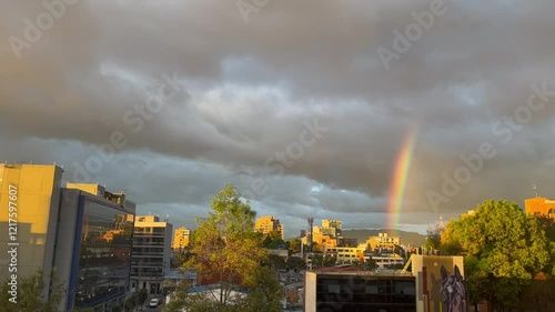 Panning shot of a city at sunset with a faint rainbow in the sky